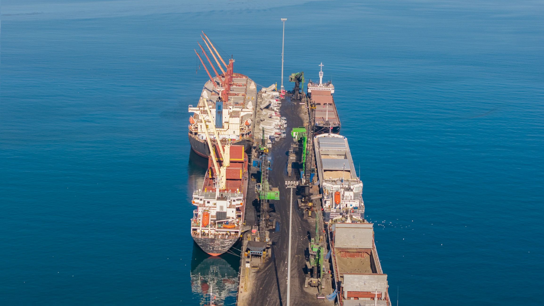Aerial view of cargo ships docked at a busy industrial port terminal
