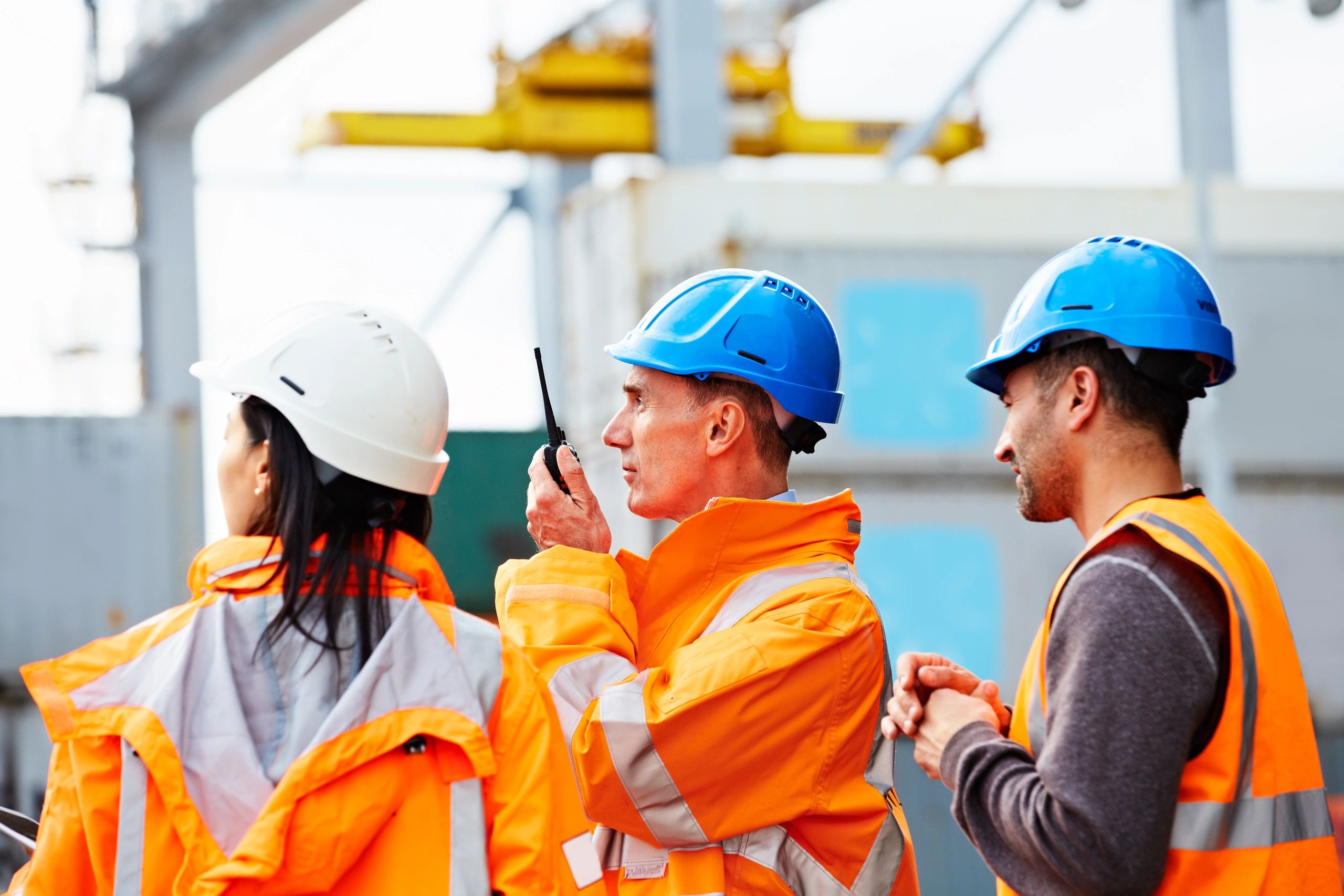 Three dock workers standing together at a commercial port